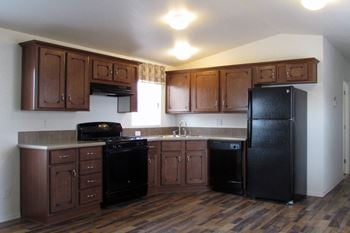 A kitchen with dark wood cabinets and black appliances